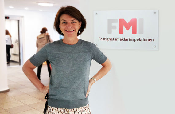 FMI:s myndighetschef Gunilla Paulsson står framför en skylt som det står Fastighetsmäklarinspektionen på.